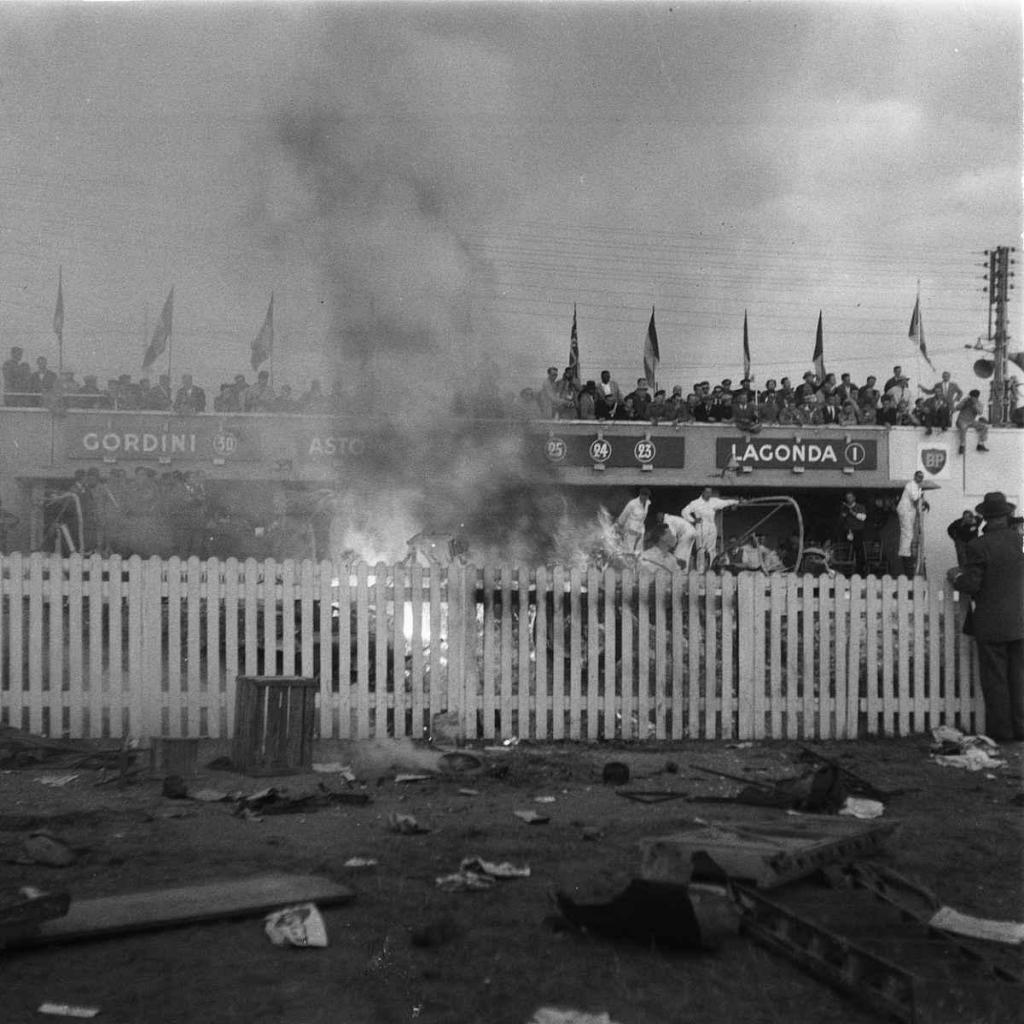 Le Mans 11. června 1955, okamžiky po katastrofě. Zbytek vozu na hliněném náspu explodoval a hořel v důsledku nadměrného tepla z karoserie ze slitiny hořčíku. Levegh při nárazu okamžitě zahynul.